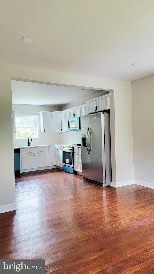 139 Wilmington Pl SE, Washington, DC 20032 - kitchen featuring stainless steel appliances, dark wood-type flooring, white cabinets, and a sink