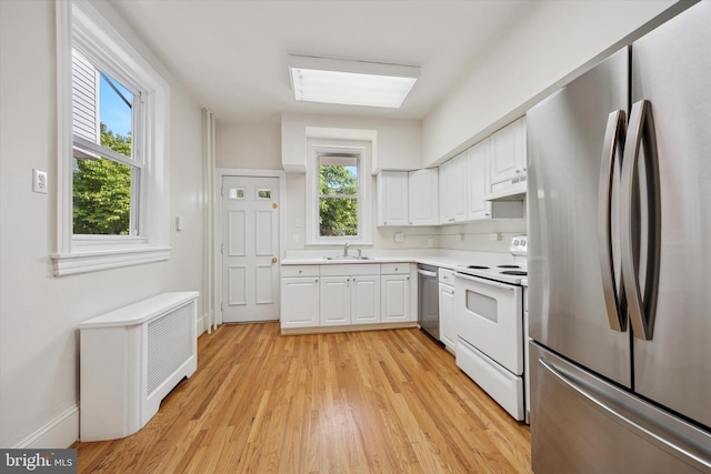 5324 Cedar Ave, Philadelphia, PA 19143 - kitchen featuring stainless steel appliances, a sink, white cabinetry, light countertops, and light wood finished floors