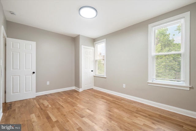 1202 Dukeland St, Baltimore, MD 21216 - unfurnished bedroom featuring light wood-style flooring, multiple windows, and baseboards