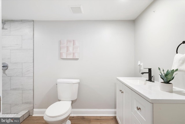 1202 Dukeland St, Baltimore, MD 21216 - bathroom with toilet, vanity, wood finished floors, tiled shower, and baseboards