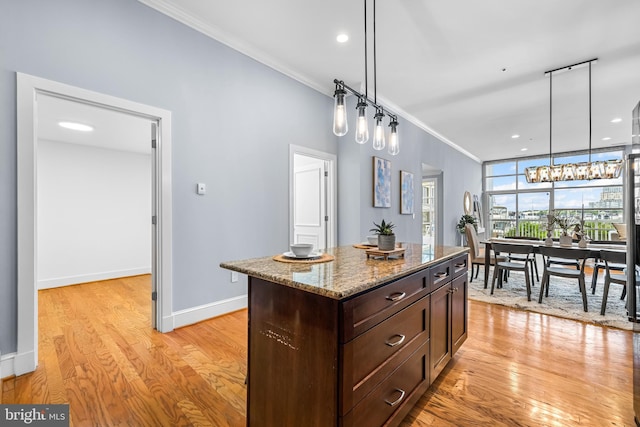 2772 Lighthouse Pt E Unit 101, Baltimore, MD 21224 - kitchen featuring ornamental molding, dark brown cabinets, light wood-type flooring, stone countertops, and hanging light fixtures