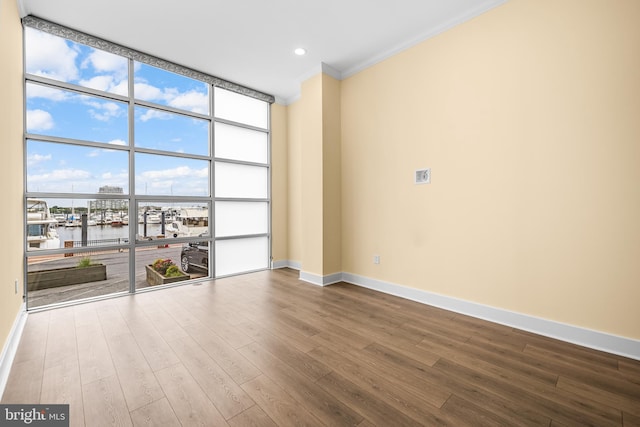 2772 Lighthouse Pt E Unit 101, Baltimore, MD 21224 - empty room featuring a water view, crown molding, floor to ceiling windows, wood finished floors, and baseboards