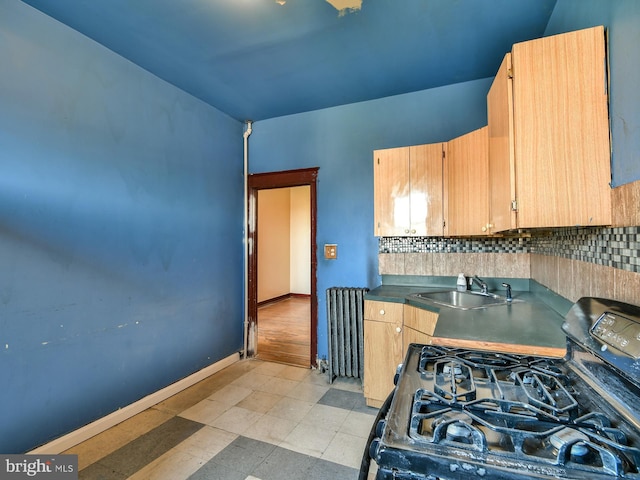 749 Bartlett Ave, Baltimore, MD 21218 - kitchen featuring radiator, black range with gas cooktop, a sink, backsplash, and baseboards