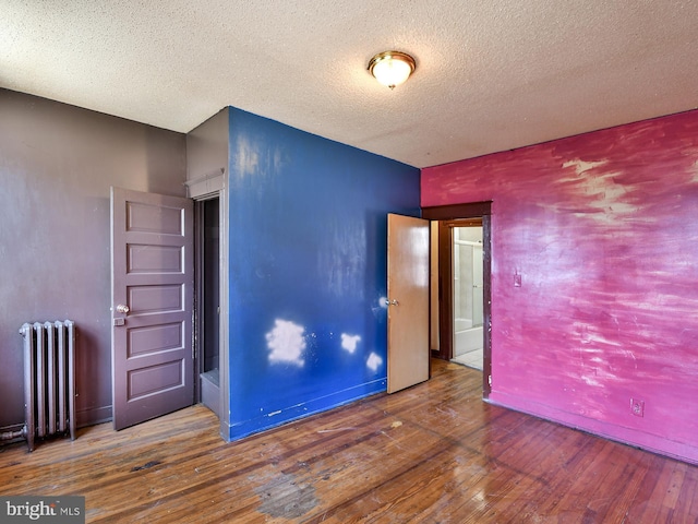 749 Bartlett Ave, Baltimore, MD 21218 - empty room with radiator heating unit, hardwood / wood-style floors, and a textured ceiling