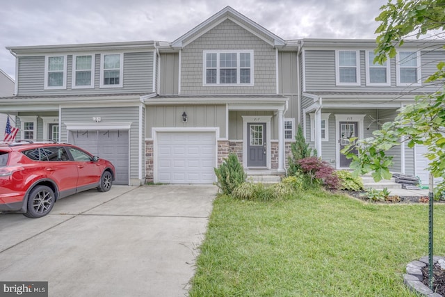 217 Tea Party Trl, Dover, DE 19901 - townhome / multi-family property with concrete driveway, a front lawn, an attached garage, board and batten siding, and stone siding
