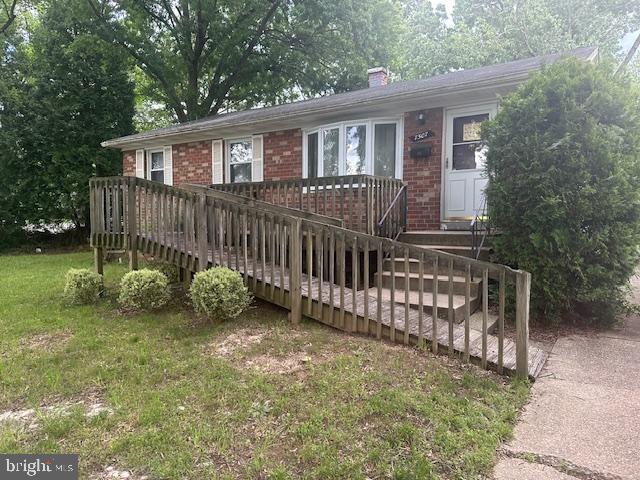 7507 Vanessa Ct, Lanham, MD 20706 - ranch-style house with brick siding, a chimney, a front lawn, and a wooden deck