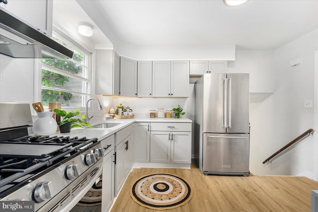 8511 Valleyfield Rd, Lutherville Timonium, MD 21093 - kitchen with appliances with stainless steel finishes, under cabinet range hood, light wood-type flooring, light countertops, and a sink