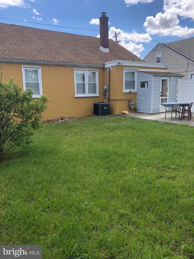 3149 Willits Rd, Philadelphia, PA 19114 - rear view of house featuring a chimney, a patio area, a lawn, stucco siding, and a shingled roof