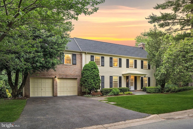 9713 Digging Rd, Gaithersburg, MD 20886 - view of front of home featuring asphalt driveway, a chimney, a yard, a garage, and brick siding