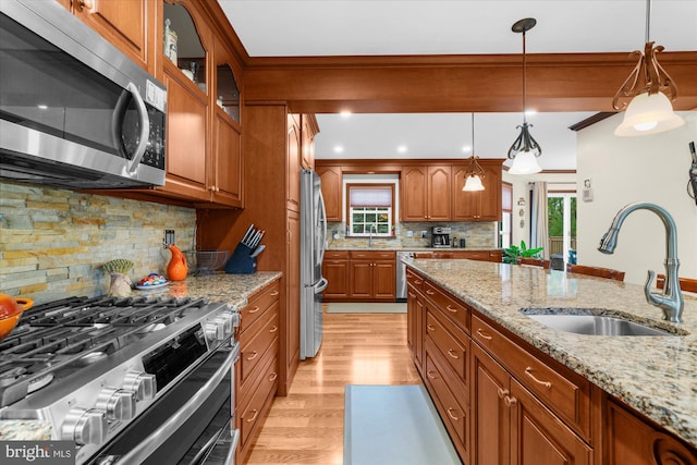 2332 Noel Cir, Pottstown, PA 19464 - kitchen with stainless steel appliances, a sink, brown cabinets, light wood-type flooring, and decorative backsplash