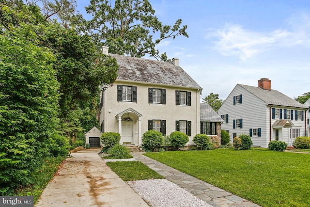 4405 Underwood Rd, Baltimore, MD 21218 - colonial inspired home featuring stucco siding, a front lawn, an outbuilding, and a chimney