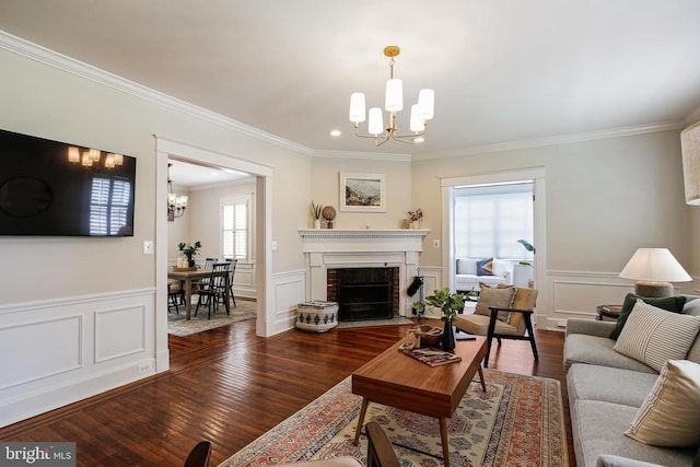 4405 Underwood Rd, Baltimore, MD 21218 - living room featuring a chandelier, ornamental molding, dark wood-style flooring, wainscoting, and a brick fireplace