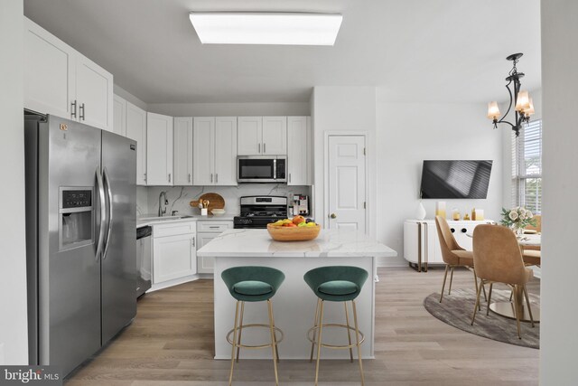44138 Allderwood Ter, Ashburn, VA 20147 - kitchen with appliances with stainless steel finishes, white cabinetry, a kitchen island, and light wood finished floors