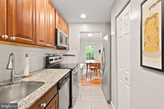 2455 Alsop Ct, Reston, VA 20191 - kitchen featuring appliances with stainless steel finishes, a sink, light tile patterned flooring, light stone counters, and backsplash
