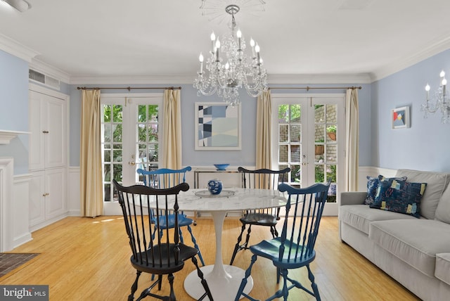 116 Cameron Mews, Alexandria, VA 22314 - dining room featuring french doors, a chandelier, light wood finished floors, a wainscoted wall, and a decorative wall