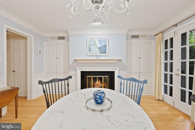 116 Cameron Mews, Alexandria, VA 22314 - dining space featuring a chandelier, light wood-type flooring, crown molding, a glass covered fireplace, and french doors