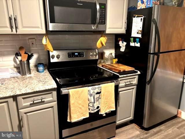 744 Cherry St, Camden, NJ 08103 - kitchen featuring stainless steel appliances, tasteful backsplash, white cabinets, and light wood-style flooring