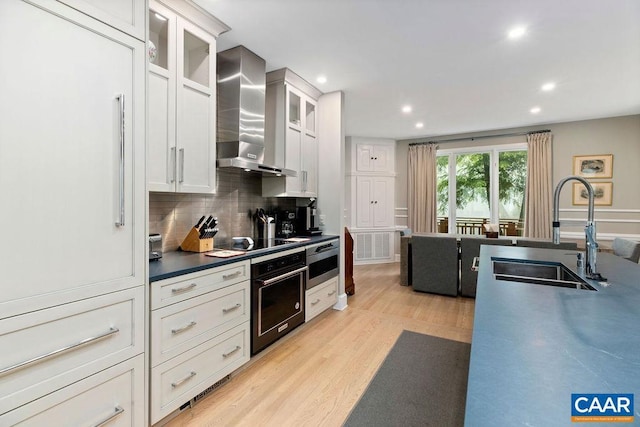 15 Trillium Close, Wintergreen Resort, VA 22967 - kitchen with black appliances, wall chimney range hood, a sink, decorative backsplash, and light wood-type flooring