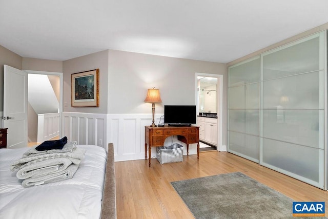 15 Trillium Close, Wintergreen Resort, VA 22967 - bedroom with light wood-type flooring, wainscoting, ensuite bathroom, and a decorative wall