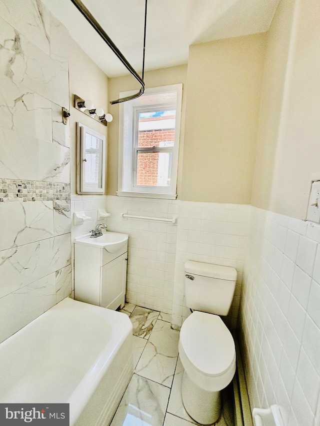 805 W Bristol St, Philadelphia, PA 19140 - bathroom featuring tile walls, marble look tile flooring, vanity, toilet, and a tub