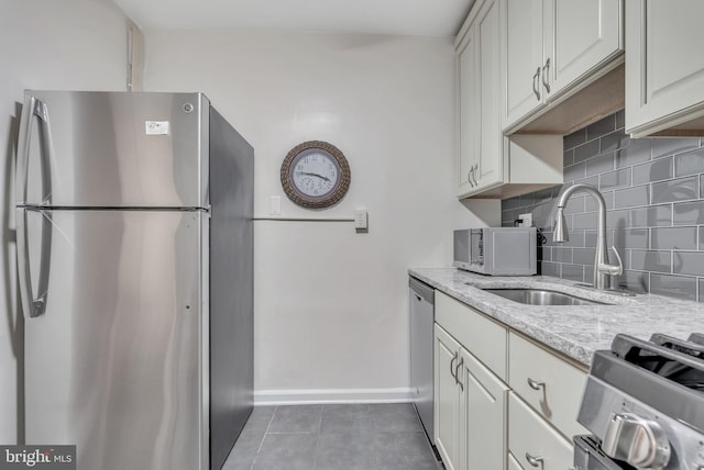4201 Cathedral Ave NW Unit 918W, Washington, DC 20016 - kitchen featuring appliances with stainless steel finishes, a sink, decorative backsplash, baseboards, and light stone countertops