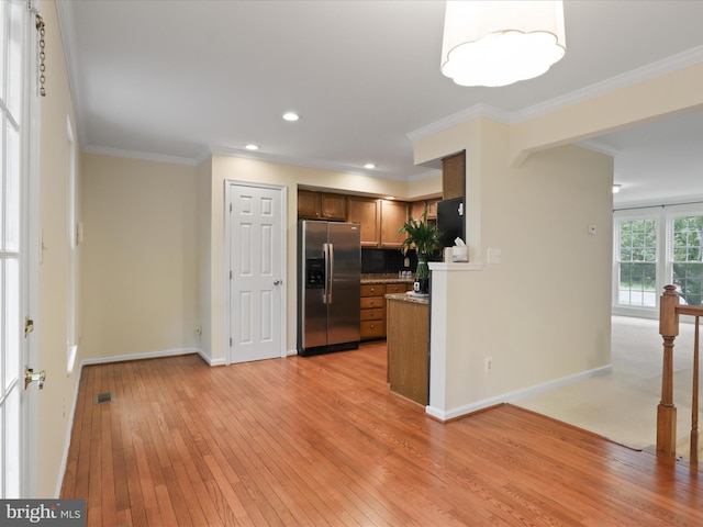 10612 Winfield Loop, Manassas, VA 20109 - kitchen with stainless steel fridge, light wood-type flooring, baseboards, crown molding, and brown cabinetry