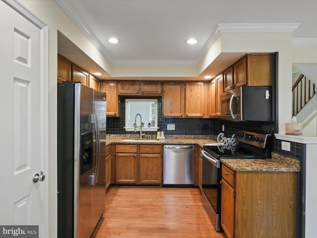 10612 Winfield Loop, Manassas, VA 20109 - kitchen with appliances with stainless steel finishes, a sink, brown cabinetry, crown molding, and light wood-style flooring