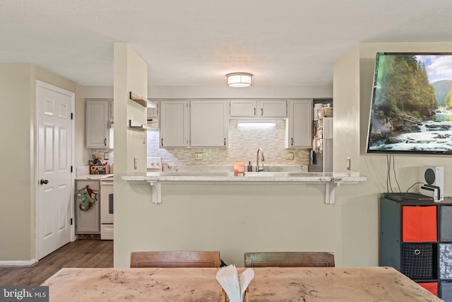 43 Cranberry Ct, Marlton, NJ 08053 - kitchen with a kitchen bar, freestanding refrigerator, dark wood-style floors, a peninsula, and decorative backsplash