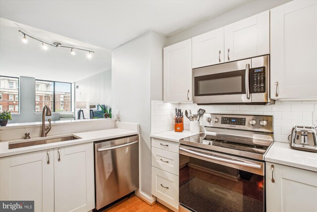 1312 Massachusetts Ave NW Unit 604, Washington, DC 20005 - kitchen featuring stainless steel appliances, a sink, light countertops, white cabinets, and backsplash