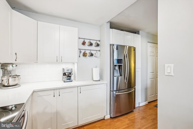 1312 Massachusetts Ave NW Unit 604, Washington, DC 20005 - kitchen with stainless steel fridge, white cabinetry, decorative backsplash, light wood-type flooring, and light countertops