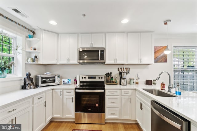 5310 B St SE, Washington, DC 20019 - kitchen featuring appliances with stainless steel finishes, a sink, white cabinets, light countertops, and light wood-style flooring