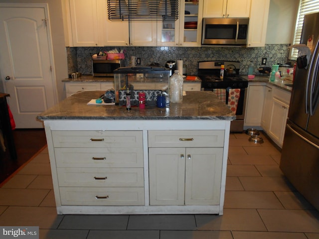 4708 Frederick Ave, Baltimore, MD 21229 - kitchen with stainless steel appliances, dark tile patterned floors, tasteful backsplash, and glass insert cabinets