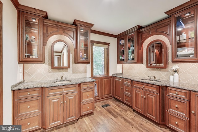 7007 Clifton Rd, Clifton, VA 20124 - kitchen with light wood-style flooring, a sink, glass insert cabinets, light stone counters, and decorative backsplash