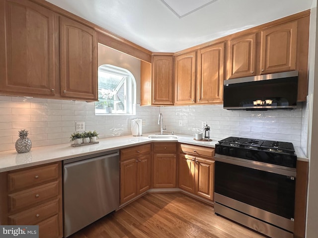 5420 Eastbourne Dr, Springfield, VA 22151 - kitchen featuring appliances with stainless steel finishes, a sink, light wood finished floors, light countertops, and tasteful backsplash