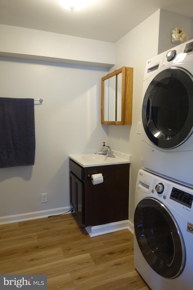 413 Dominion Rd, Chester, MD 21619 - laundry room with stacked washer and clothes dryer, light wood-style flooring, baseboards, and cabinet space