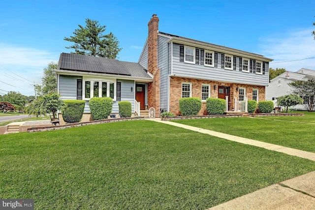 199 Applegate, Hamilton, NJ 08690 - view of front facade featuring solar panels, a front lawn, a chimney, and brick siding