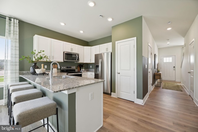 112 Pomo Ln, Winchester, VA 22602 - kitchen featuring appliances with stainless steel finishes, a sink, a peninsula, light stone counters, and white cabinetry