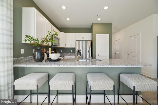 112 Pomo Ln, Winchester, VA 22602 - kitchen with appliances with stainless steel finishes, a sink, a peninsula, white cabinets, and light stone countertops
