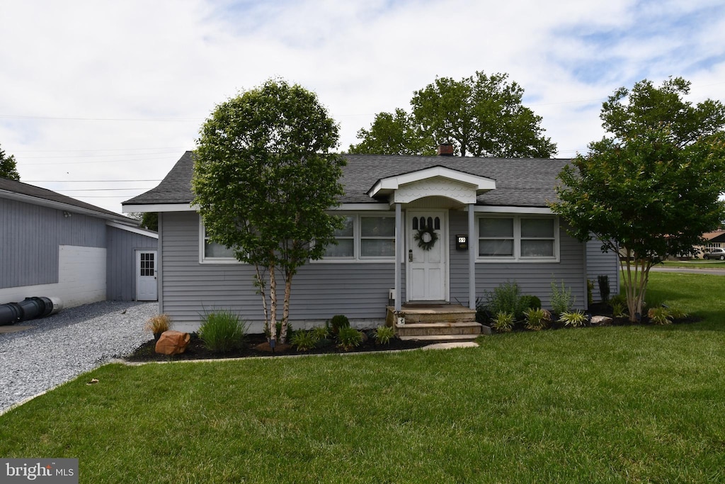 69 Walker Ave, Carneys Point, NJ 08069 - view of front of house featuring roof with shingles, a front yard, and an outbuilding