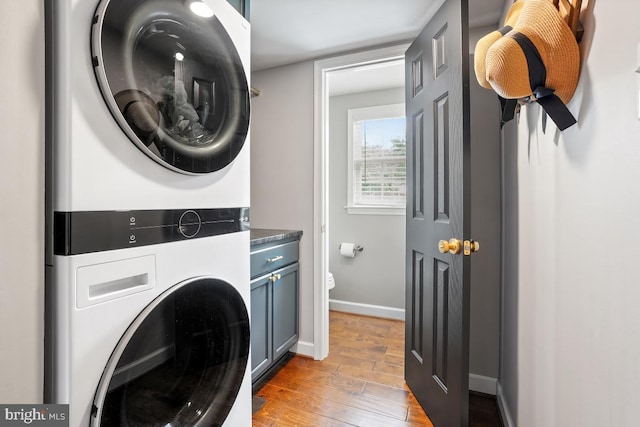 9977 Mallow Ct, Manassas, VA 20110 - laundry area with estacked washer and dryer, cabinet space, light wood-type flooring, and baseboards