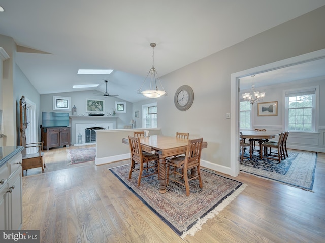 4387 Stepney Dr, Gainesville, VA 20155 - dining room with a skylight, light wood-type flooring, a fireplace, vaulted ceiling, and a chandelier