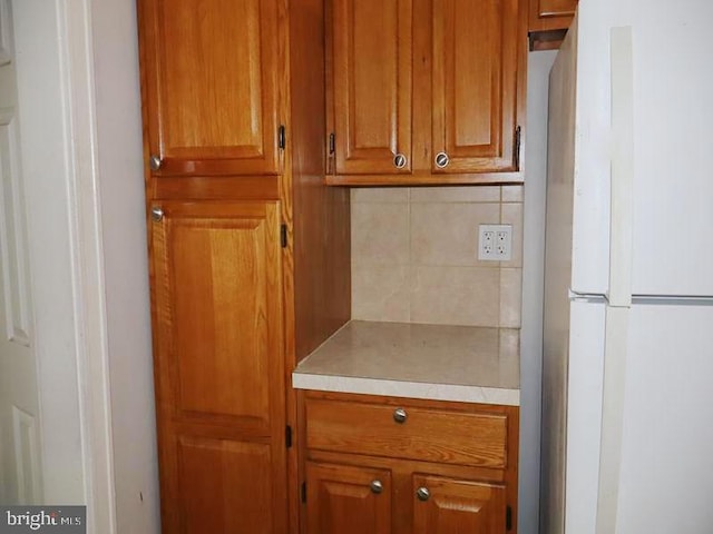 2130 Melvin St, Philadelphia, PA 19131 - kitchen with freestanding refrigerator, light countertops, backsplash, and brown cabinetry