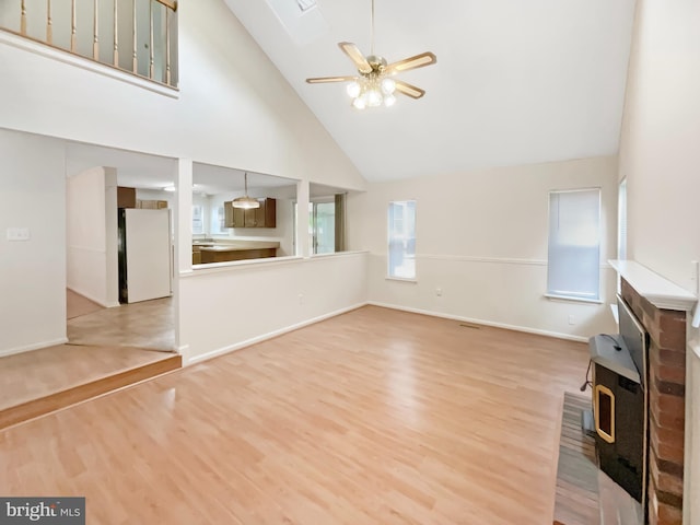 6502 Elk Ct, Waldorf, MD 20603 - unfurnished living room with a wood stove, high vaulted ceiling, a ceiling fan, light wood finished floors, and baseboards