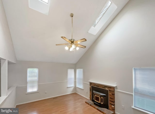 6502 Elk Ct, Waldorf, MD 20603 - unfurnished living room with a wood stove, a skylight, wood finished floors, a ceiling fan, and high vaulted ceiling