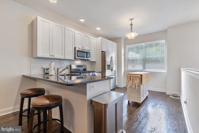 605 Apple St, Conshohocken, PA 19428 - kitchen featuring stainless steel appliances, a sink, a peninsula, dark wood-style flooring, and a breakfast bar area