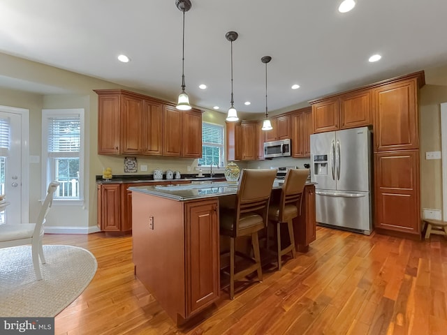 21143 Catnip Ct, Leonardtown, MD 20650 - kitchen with appliances with stainless steel finishes, light wood-style flooring, brown cabinetry, a kitchen island, and dark countertops