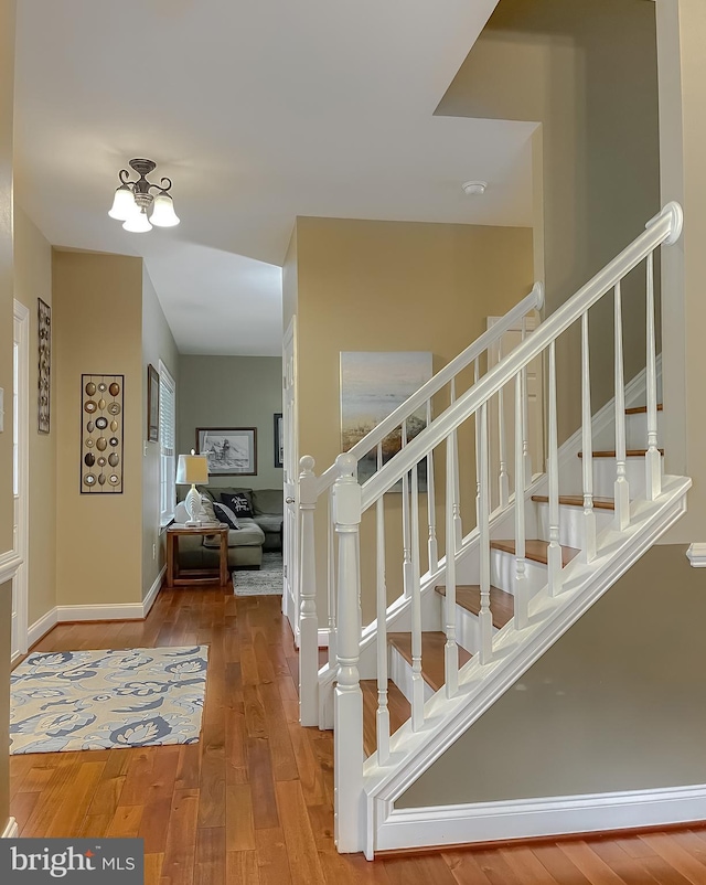 21143 Catnip Ct, Leonardtown, MD 20650 - stairway featuring wood-type flooring, baseboards, and a chandelier
