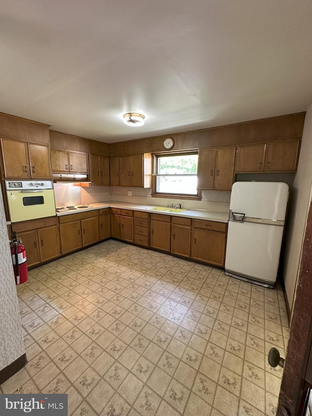 120 Lindsey Ave, Runnemede, NJ 08078 - kitchen with white appliances, light countertops, under cabinet range hood, a sink, and brown cabinets