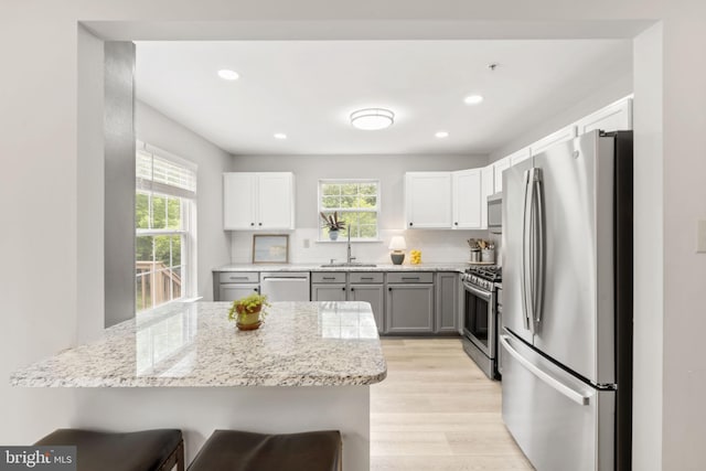 440 Glenn Rose Cir, King Of Prussia, PA 19406 - kitchen with stainless steel appliances, light stone countertops, a kitchen bar, light wood finished floors, and a sink