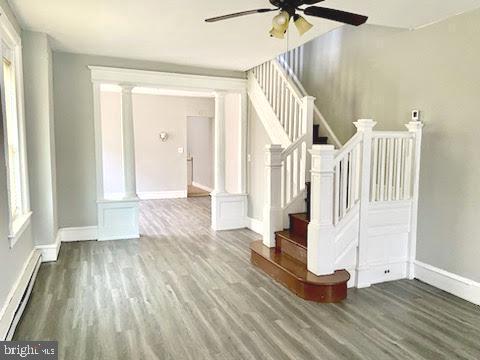 1364 Park Blvd, Camden, NJ 08103 - unfurnished living room featuring a ceiling fan, a baseboard heating unit, decorative columns, and wood finished floors